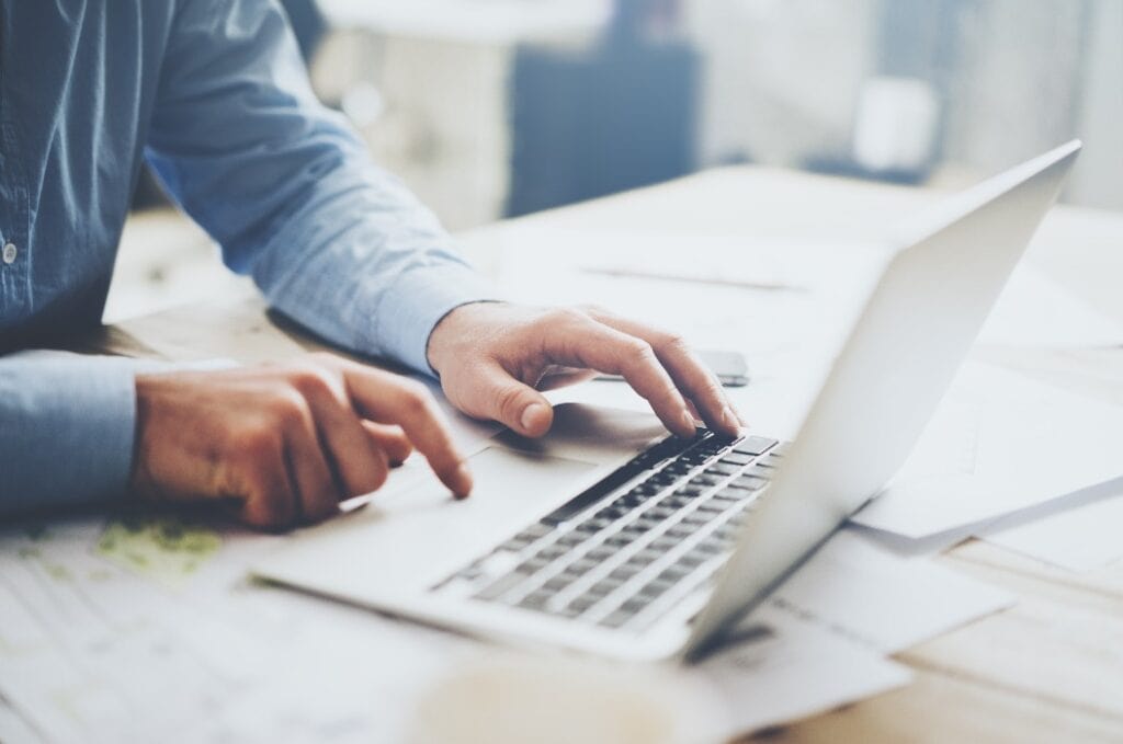 Businessman working laptop for new architectural project. Generic design notebook on the table. Blurred background, horizontal mockup.