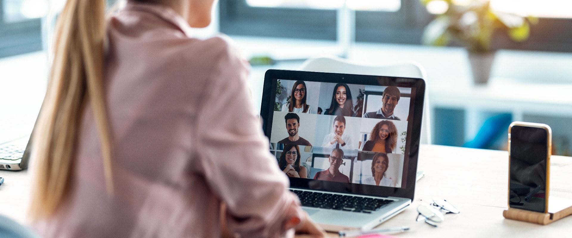 Female employee speaking on video call with diverse colleagues on online briefing with laptop at home.