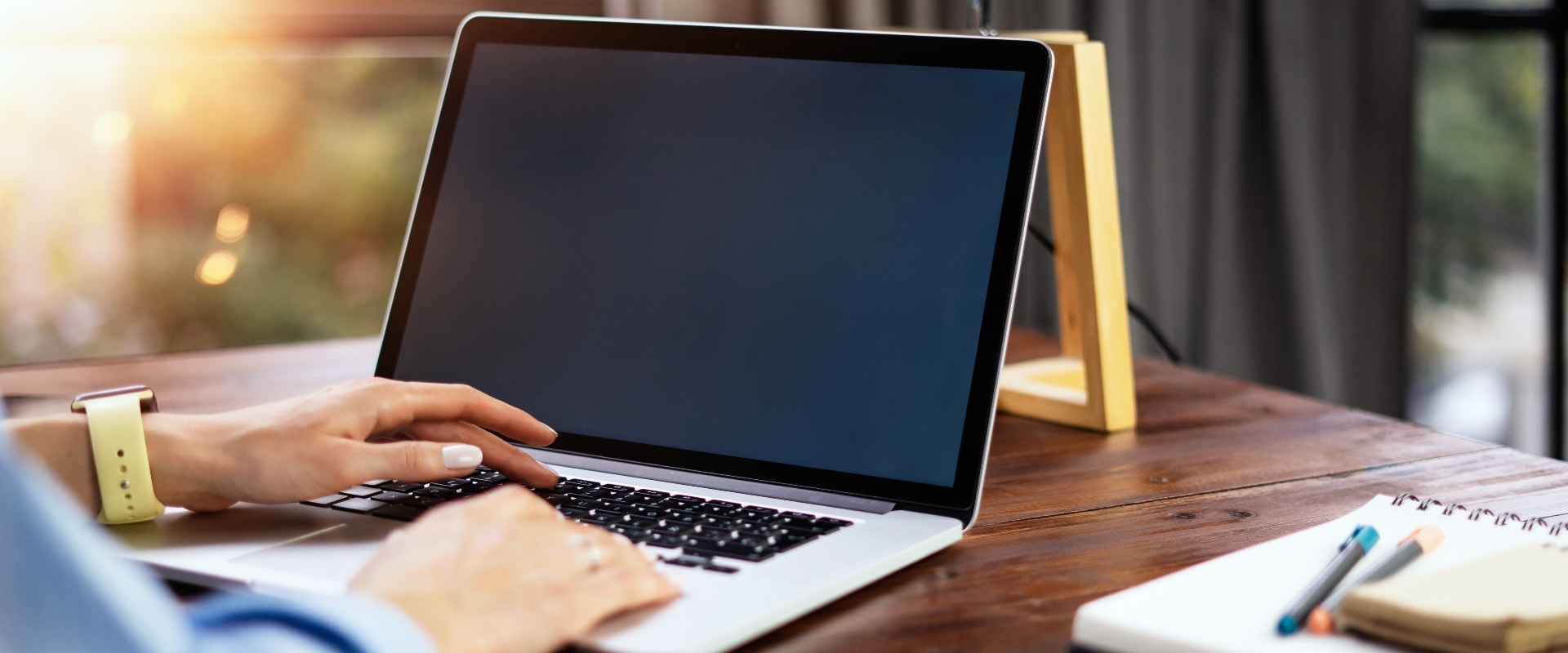 Mockup image of a woman using laptop with blank screen on wooden table